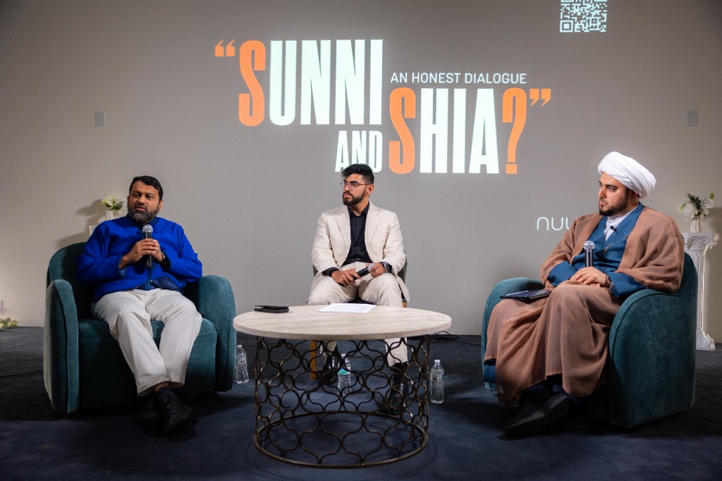Panelists seated beneath a projected Sunni and Shia dialogue title