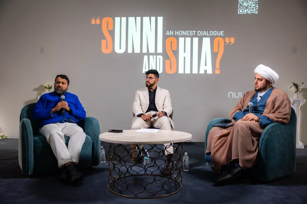 Panelists seated beneath a projected Sunni and Shia dialogue title